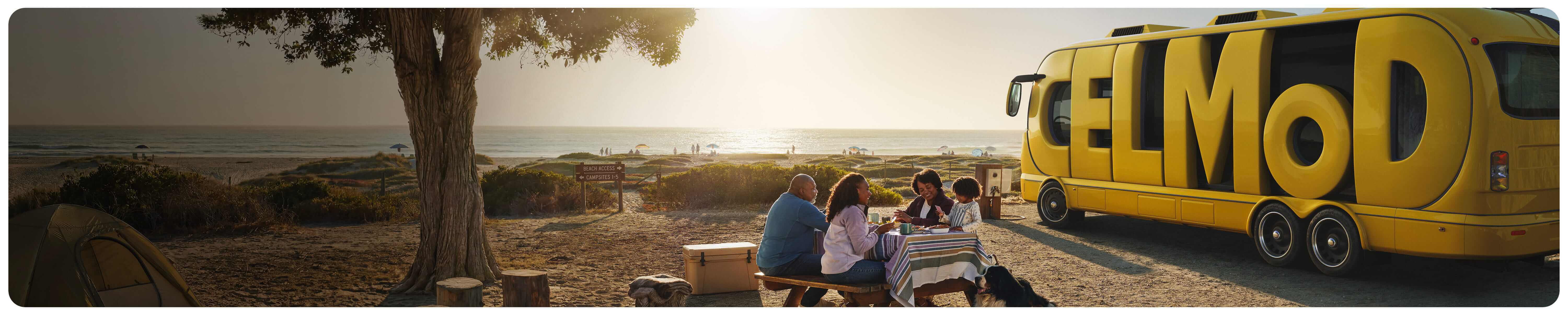 Family at a picnic table with a CELMoD RV in background
