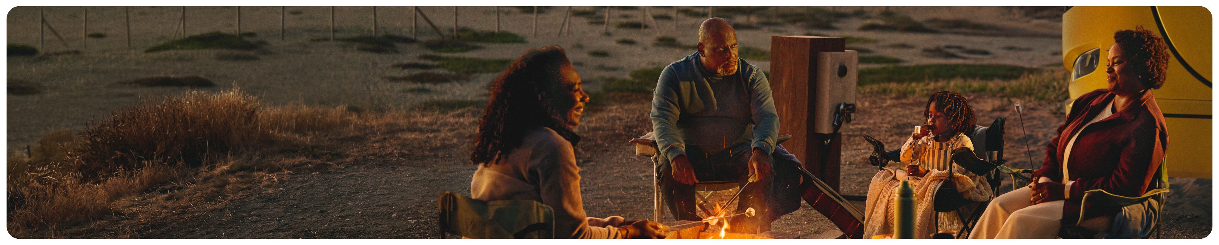 A family around a campfire with a CELMoD RV in background